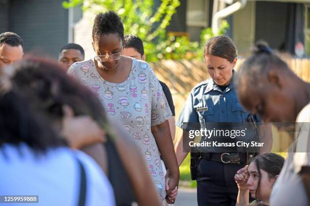 Kansas City Police Chief Stacey Graves held hands with Cherron Barney, left, and another woman as people gathered in the street to pray after three...