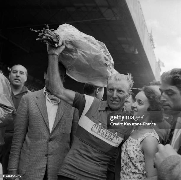 André Darrigade, vainqueur de la dernière étape, brandit un bouquet de fleurs à son arrivée au Parc des Princes, à Paris, France le 20 juillet 1957.