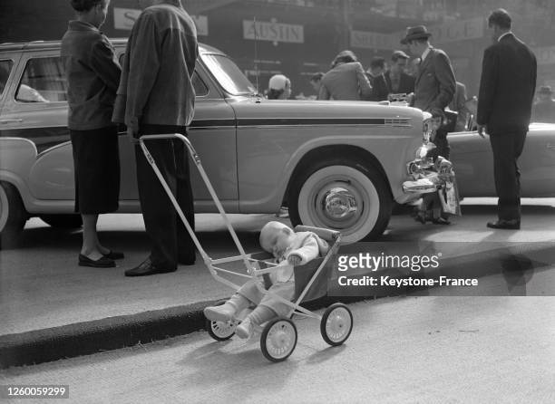 Un bébé endormi dans sa poussette dans les allées du salon de l'Auto, à Paris, France le 5 octobre 1957.