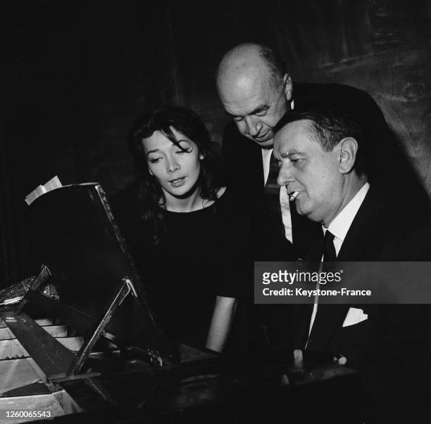 Juliette Gréco interprétant la chanson 'Bonjour Tristesse' sous la conduite de Georges Auric , derrière eux, le metteur en scène Otto Preminger, à...