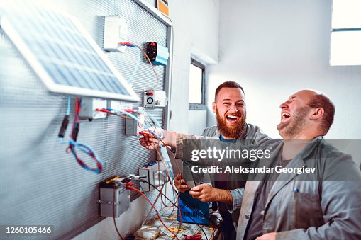 Smiling Workers Having Fun While Testing Photovoltaic Panel Cells In Factory Smiling Workers Having Fun While Testing Photovoltaic Panel Cells In Factory