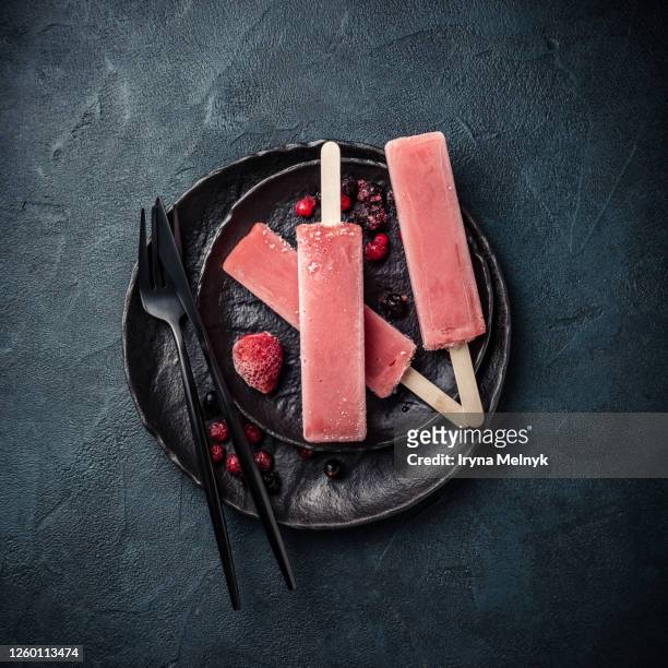 overhead shot of homemade frozen popsicles made with oragnic fresh berries, raspberries, strawberries, currants, blueberries on black plate. - gelato stock pictures, royalty-free photos & images