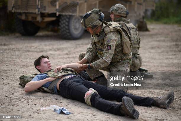 Solider from the Royal Anglian Regiment treats a "casualty" during a military exercise on Salisbury Plains on July 23, 2020 near Warminster, England....