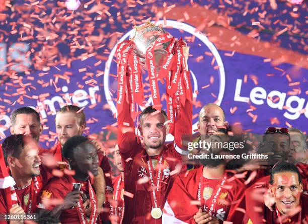 Jordan Henderson of Liverpool holds the Premier League Trophy aloft along side Mohamed Salah as they celebrate winning the League during the...