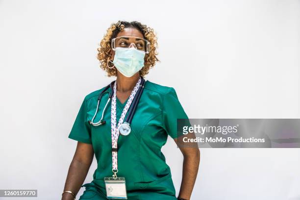studio portrait of female doctor/healthcare worker - dreiviertelansicht stock-fotos und bilder