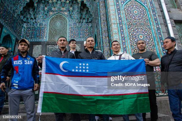 Muslims take photos with the flag of Uzbekistan near the mosque at Kronverksky Prospekt after the end of prayers during the celebration of Eid...