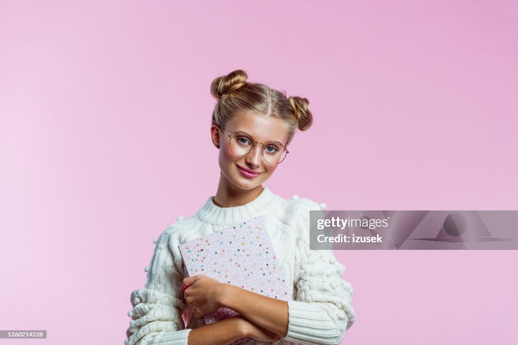 Beautiful teenege girl holding pink diary