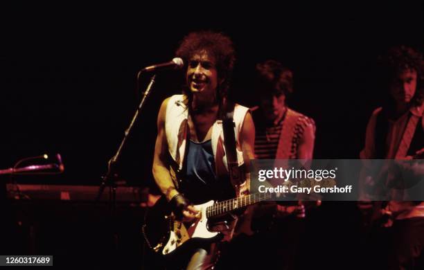 American Folk and Pop musician Bob Dylan plays guitar as he performs onstage during the 'True Confessions Tour' at Madison Square Garden, New York,...