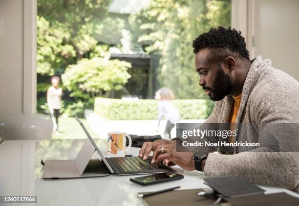 black man using digital tablet working from home - daily life in canada stockfoto's en -beelden