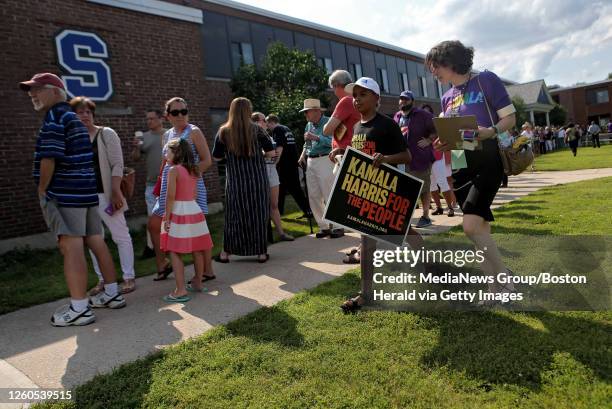 Young supporter carries a campaign sign past the line of people queuing up tho hear Democratic candidate for President, Kamala Harris, speak at an...