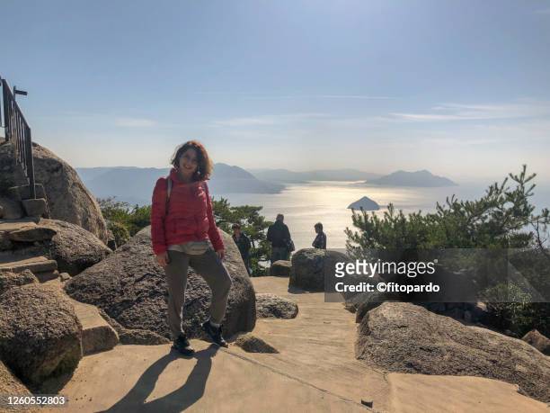an american woman posing in front of a view from top of miyajimacho island - miyajima stock pictures, royalty-free photos & images