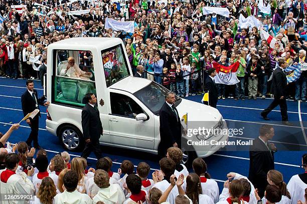 Pope Benedict XVI greets visitors while riding in the Popemobile upon his arrival at Olympiastadion stadium, where he later gave a Catholic mass for...