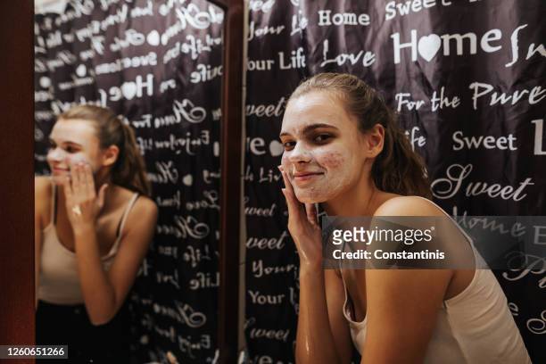 lächelnteenage mädchen reinigung ihr gesicht mit seife im badezimmer - frau gesicht schaum stock-fotos und bilder