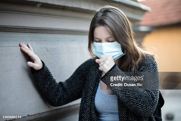 young woman coughing under the mask - symptom stock pictures, royalty-free photos & images