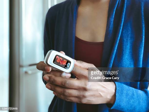 woman uses pulse oximeter - puls oxymeter stock-fotos und bilder