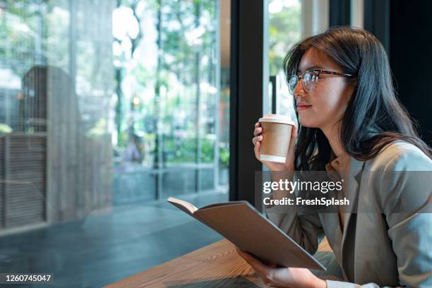 feliz empresaria asiática escribiendo un plan semanal en su agenda antes de ir a la oficina - monday fotografías e imágenes de stock