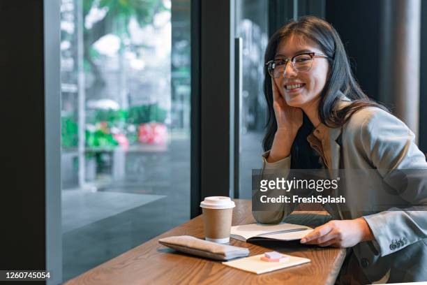happy asian businesswoman writing a weekly plan in her agenda before going to the office - monday coffee stock pictures, royalty-free photos & images