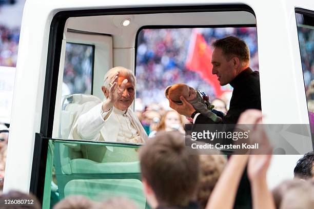 Pope Benedict XVI greets visitors while his assistent Georg Gaenswein shows a baby during riding in the Popemobile upon his arrival at Olympiastadion...