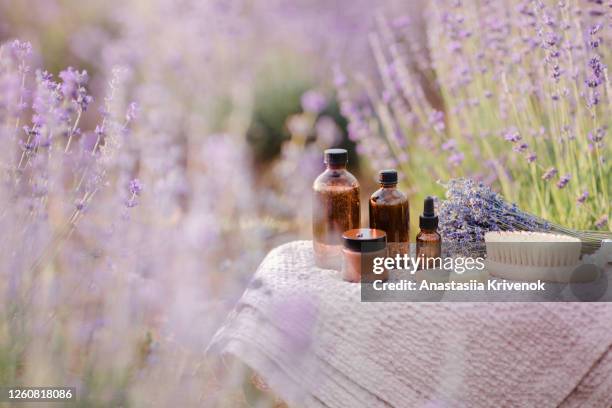 organic cosmetics bottles, essential oil and soap in lavender field in the summer. aromatherapy. skincare concept. - herbal water stock-fotos und bilder