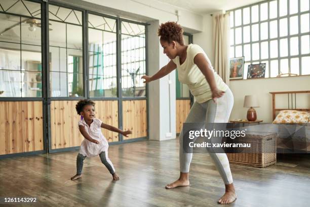 young mother and daughter doing dance exercises at home - family side by side stock pictures, royalty-free photos & images