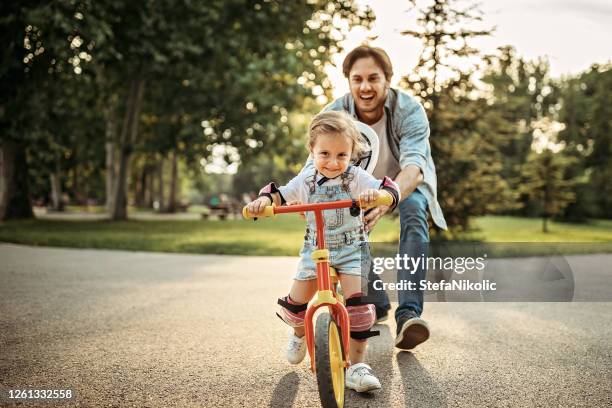 vader die zijn dochter leert hoe te om een fiets te drijven - kids on bikes stockfoto's en -beelden