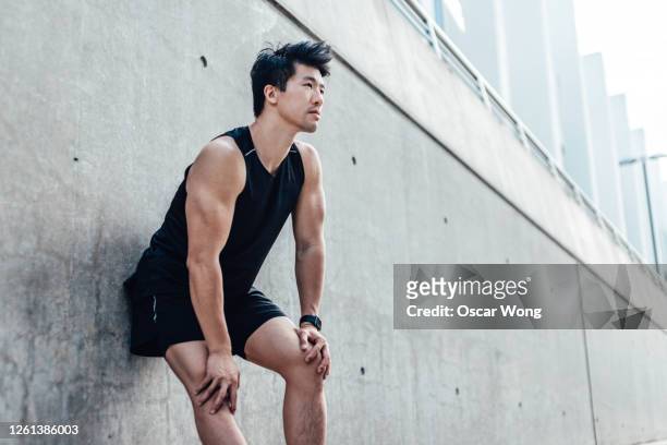 motivated young man taking a break after running in the city - asian exercise bildbanksfoton och bilder