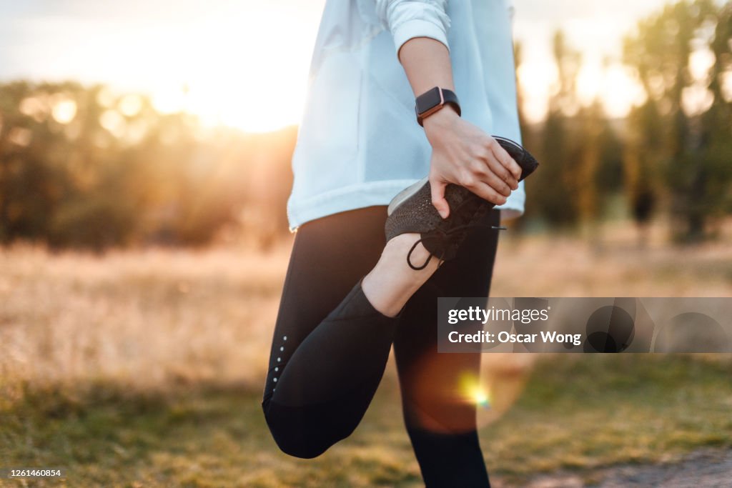 Young Woman Stretching Legs In The Park After Exercise