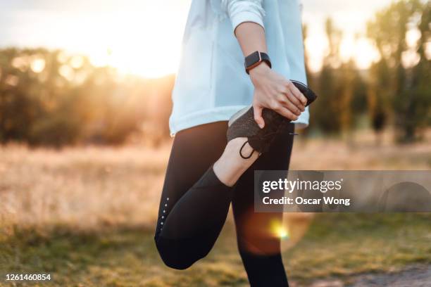 young woman stretching legs in the park after exercise - estirándose fotografías e imágenes de stock