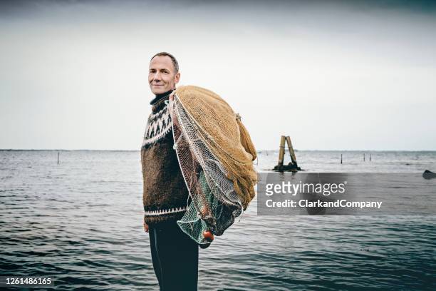 pêcheur de crevettes mettant ses filets dans la mer. - fisherman stock photos et images de collection