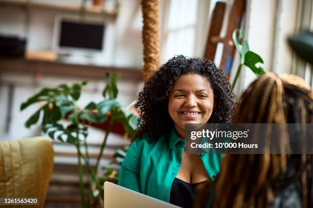mixed race woman smiling at colleague in office meeting - entrevista coletiva fotografías e imágenes de stock