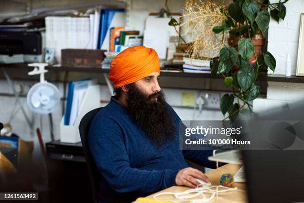 asian man using computer at desk in office - sikhism stock-fotos und bilder