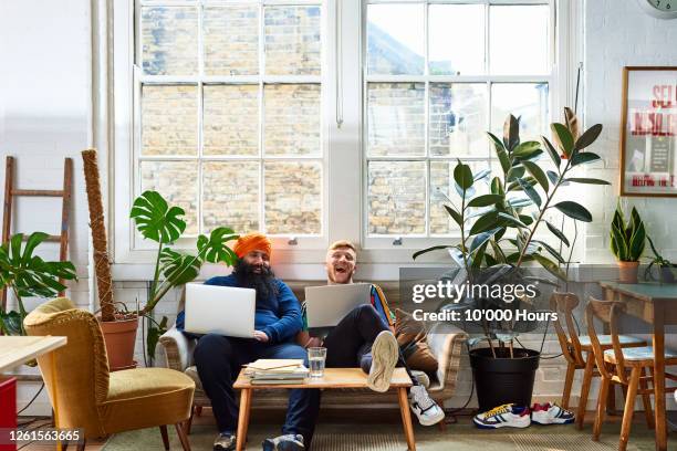 multi ethnic colleagues laughing on sofa at work - sikhism stock-fotos und bilder