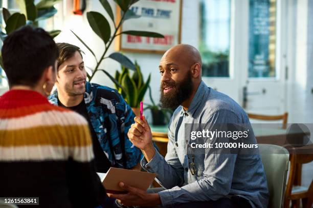 man with beard discussing with team - consigli foto e immagini stock