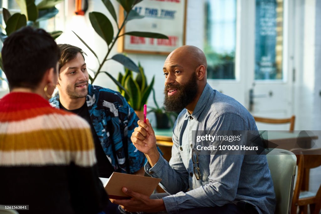 Man with beard discussing with team