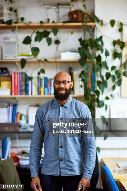 black mid adult entrepreneur in office smiling at camera - completely bald stockfoto's en -beelden