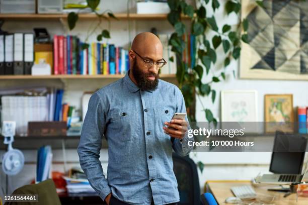 mid adult entrepreneur text messaging in office - bald man glasses beard stock pictures, royalty-free photos & images