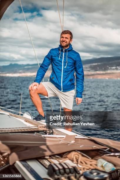 portrait of smiling man standing aboard a sailing yacht. - hand on knee stock pictures, royalty-free photos & images