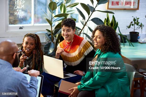 business women talking to male colleague, informal meeting - milleniumgeneratie stockfoto's en -beelden