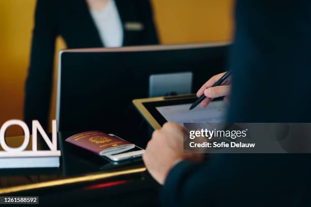 businessman checking in at hotel reception - recepcionista hotel fotografías e imágenes de stock
