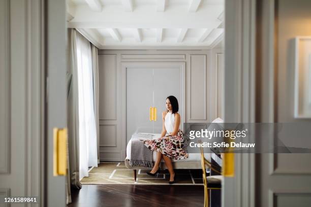fashionable woman beside window in suite - bedroom suite stock-fotos und bilder