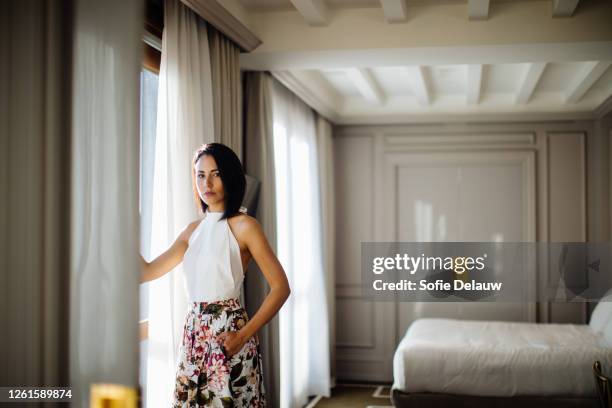 fashionable woman beside window in suite - halter top foto e immagini stock