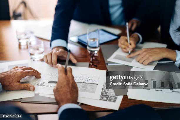 businessmen and woman at boardroom table working on paperwork, cropped - actualización comunicación fotografías e imágenes de stock