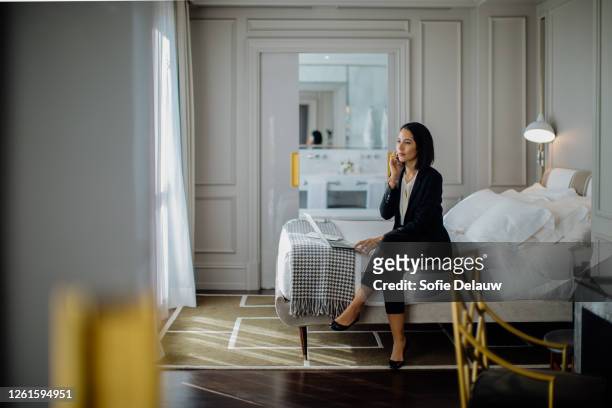 businesswoman using smartphone and laptop in suite - bedroom suite stock-fotos und bilder