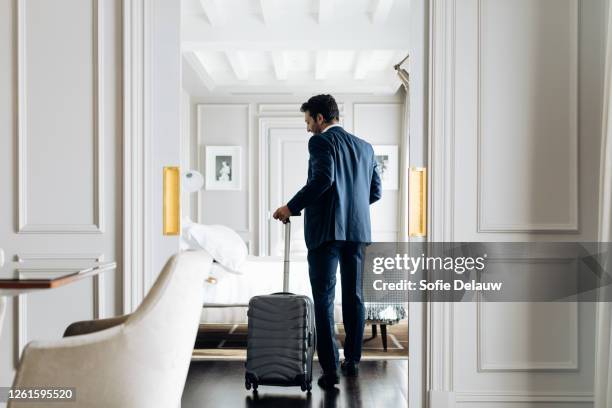 businessman with wheeled luggage in suite - habitación de hotel fotografías e imágenes de stock