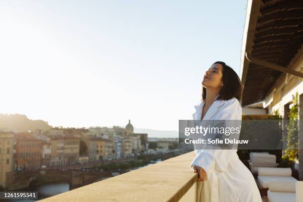 woman enjoying sun on hotel balcony, florence, toscana, italy - italian woman stock-fotos und bilder