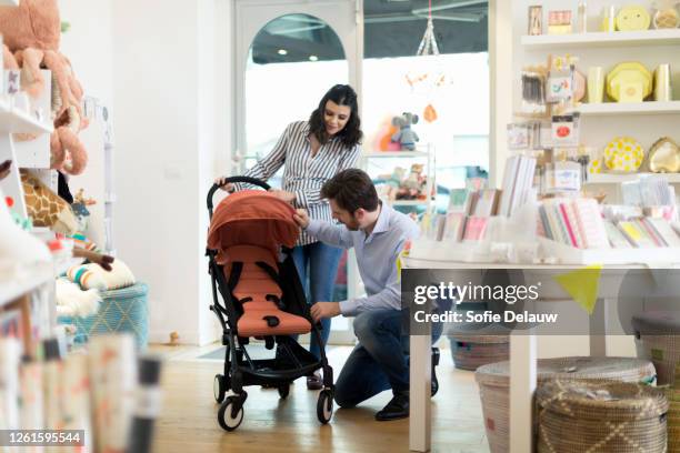 husband and pregnant wife shopping for pram - kinderwagen stockfoto's en -beelden