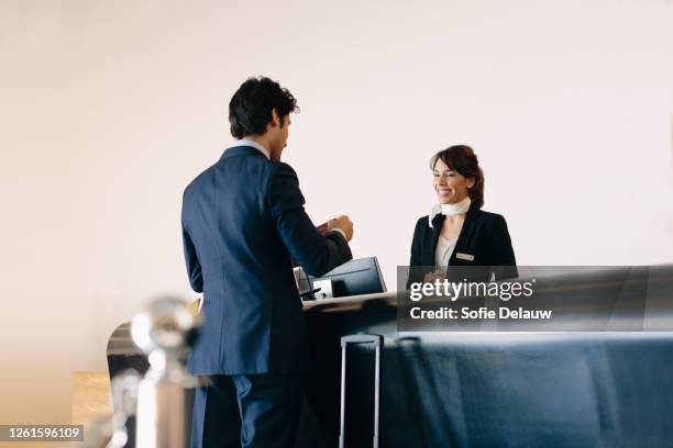 businessman making contactless payment at hotel reception - airport check in stock-fotos und bilder