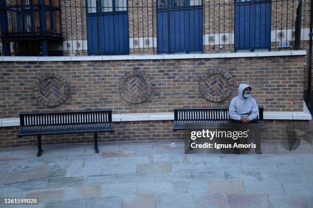 man wearing face mask sitting on bench in shoreditch, london during corona virus crisis. - lockdown england stock pictures, royalty-free photos & images