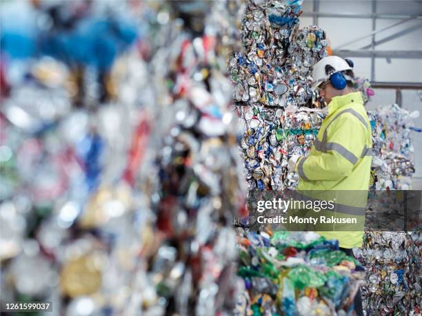 worker inspecting mixed waste in waste recycling plant. - cannette photos et images de collection