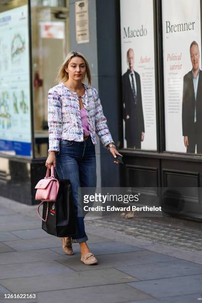 Guest wears a tweed jacket, blue jeans, a pink top, a pink quilted Chanel bag, beige flat shoes, during London Fashion Week September 2019 on...